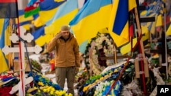 A Ukrainian serviceman salutes standing between the graves of soldiers during the funeral of Hennadii Kovshyk, who was killed on the frontline in eastern Ukraine, in Kharkiv, Ukraine, Feb. 16, 2023.