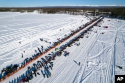 FILE - A competitor mushes across Willow Lake during the Iditarod Trail Sled Dog Race, in Willow, Alaska, March 6, 2022.