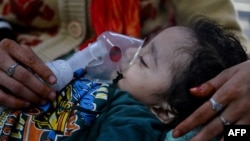 FILE - A mother assists her child to breathe with the help of a nebulizer at the emergency ward of the government-run Chacha Nehru Bal Chikitsalaya children hospital in New Delhi, India, Nov. 7, 2023. 