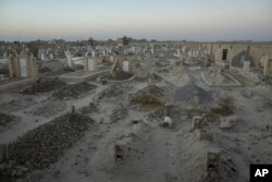 An Afghan Shiite cemetery, where a large number of Shiite migrants who were killed while trying to cross the border are buried, lies on the outskirts of Zaranj city, Afghanistan, Monday, Dec. 25, 2023. (AP Photo/Ebrahim Noroozi)