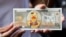 FILE - A protester shows a fake banknote depicting a duck during a pro-democracy rally demanding Thailand's king hands back royal assets to the people, reforms on monarchy, Bangkok, Nov. 25, 2020. 