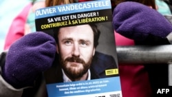 FILE - A demonstrator holds a flier with a photo of detained Belgian aid worker Olivier Vandecasteele, at a rally organized by Amnesty International and a support committee to ask for his liberation, in Brussels, Jan. 22, 2023.