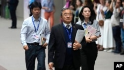 Liu Zhenmin, China's special envoy for climate change, arrives past demonstrators to attend a new session of talks at the COP28 U.N. Climate Summit, Dec. 11, 2023, in Dubai, United Arab Emirates.