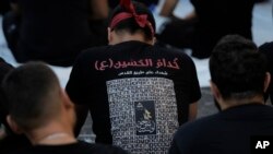 A supporter of the Iranian-backed Hezbollah group wears a T-shirt with pictures of Hezbollah fighters killed in battles with Israel, during activities marking the Shiite Muslim holy day of Ashoura, in suburban Beirut, Lebanon, July 17, 2024.