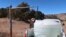 FILE - Phillip Yazzie waits for a water drum in the back of his pickup truck to be filled in Teesto, Arizona, on the Navajo Nation, Feb. 11, 2021. 