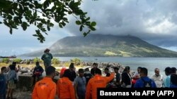 Masyarakat di Sitaro, Sulawesi Utara memandangi gunung berapi Gunung Ruang yang mengeluarkan asap. (Foto: Basarnas via AFP)