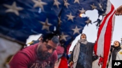 A protester burns a U.S. flag as others shout slogans against Israel and the United States during a protest in solidarity with the Palestinian people in Gaza in Beirut, Lebanon, March 2, 2024.