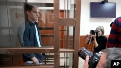 Wall Street Journal reporter Evan Gershkovich stands in a glass cage in a courtroom at the Moscow City Court in Moscow, Oct. 10, 2023.