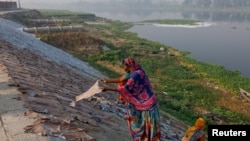 FILE - Women dry cattle hides outside a tannery near water that feeds into the Buriganga River on the outskirts of Dhaka, Bangladesh, March 7, 2023.