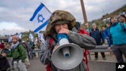 FILE - Israeli military reservists protest against the plans by Prime Minister Benjamin Netanyahu's new government to overhaul the judicial system, on a freeway from Tel Aviv to Jerusalem, Feb. 9, 2023. 