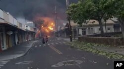 People watch as smoke and flames fill the air from raging wildfires on Front Street in downtown Lahaina, Maui on Tuesday, Aug. 8, 2023. (Alan Dickar via AP) Keep aspect ratio