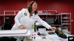 Defense POW/MIA Accounting Agency forensic anthropologist Carrie Brown looks at objects in a lab at Offutt Air Force Base, May 20, 2024, in Bellevue, Neb. 
