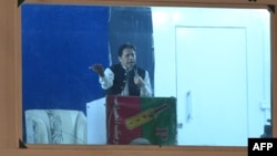 Pakistan's former prime minister Imran Khan speaks to his supporters from behind a bulletproof shield at a rally in Lahore early on March 26, 2023.