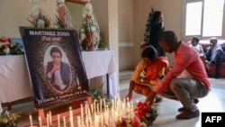 FILE - Mourners place candles in a room of Radio Amplitude FM where a portrait of journalist Martinez Zogo has been placed to pay tribute to him, in the Elig Essono district in Yaounde, Jan. 23, 2023. 