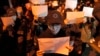 FILE - Protesters hold up blank pieces of paper and chant slogans as they march to protest strict anti-virus measures in Beijing, Nov. 27, 2022.