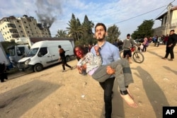 A Palestinian evacuates a wounded child after an Israeli strike on Al Zawayda, central Gaza Strip, Dec. 28, 2023.