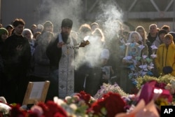 An Orthodox priest conducts a service at a makeshift memorial in front of the Crocus City Hall in the outskirts of Moscow, March 25, 2024.
