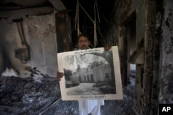A government employee displays an old picture to media members inside the Radio Pakistan building burnt in the Wednesday's clashes between police and the supporters of Pakistan's former Prime Minister Imran Khan, in Peshawar, Pakistan, May 11, 2023.