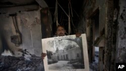 A government employee displays an old picture to media members inside the Radio Pakistan building burnt in the Wednesday's clashes between police and the supporters of Pakistan's former Prime Minister Imran Khan, in Peshawar, Pakistan, May 11, 2023.