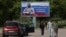 FILE - People walk near a banner in support of the Russian Army, in the town of Vyborg, Leningrad Region, Russia, May 28, 2023. The banner reads "We love you! We are proud of you! We are waiting for you with a victory!"