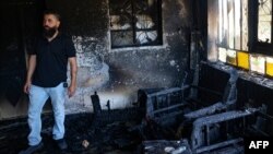 A man stands inside a home set on fire by Israelis in Turmus Ayya near the occupied West Bank city of Ramallah, June 21, 2023. A resident of Turmus Ayya told AFP around "200 settlers" attacked the Palestinian village.