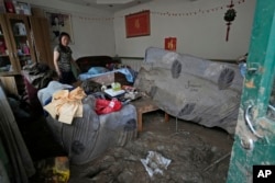 Resident Li Mingle recovers her belongings from a mud-caked room after floods swept through the village on the outskirts of Beijing, Aug. 4, 2023.