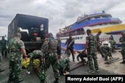 TNI memuat barang ke dalam kapal saat mereka menuju ke pulau dekat gunung berapi Gunung Ruang di pelabuhan Manado, Sulawesi Utara, pada 18 April 2024. (Foto: Ronny Adolof BUOL/AFP)