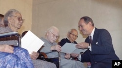 FILE - Then-Attorney General Dick Thornburgh presents $20,000 checks to three elderly Japanese Americans interned during World War II, during a ceremony at the Justice Department in Washington, Oct. 9, 1990.
