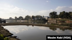 Local residents of the Rajbagh neighborhood of Srinagar on the Indian side of Kashmir fish on an uneven surface of a riverbed in Jhelum on Sept. 24, 2023.