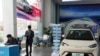 Tim marketing dari produsen mobil listrik BYD berdiri di dekat mobil listrik pabrikan tersebut di sebuah showroom di Beijing, pada 10 April 2024. (Foto: AP/Ng Han Guan)