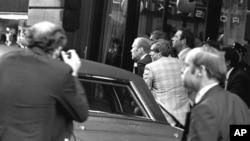FILE - President Ford ducks behind his limousine and is hustled into the vehicle after a shot was fired as he left the St. Francis Hotel in San Francisco, Sept. 22, 1975.