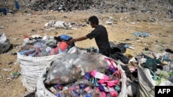 FILE - This file photo taken on June 5, 2020 shows a garbage collector gathering recyclable plastic at the Ban Tarn landfill site in the northern Thai province of Chiang Mai. 