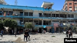 Palestinians inspect the site of an Israeli strike on a UNRWA school sheltering displaced people, amid the Israel-Hamas conflict, in Nuseirat refugee camp in the central Gaza Strip, June 6, 2024. 