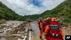 In this photo released by Xinhua News Agency, rescue workers gather aftermath of a mudslide in Weiziping village of Luanzhen township on the outskirts of Chang'an district, Xi'an of northwestern China's Shaanxi Province, Aug. 12, 2023. 