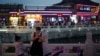 A woman looks at her phone at Shichahai lake pub area in Beijing, July 16, 2024.