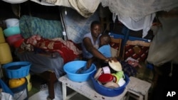 Jacinter Awino, 33, holds her son as she cleans utensils in the Kibera slum of Nairobi, Kenya, May 28, 2024. 