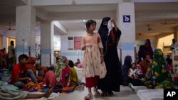 A child suffering from dengue is helped by a family member as she walks inside the dengue ward of Mugda Medical College and Hospital in Dhaka, Bangladesh, Aug. 10, 2023.
