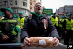 FILE - A woman holds bread during a farmers protest in Bucharest, Romania, April 7, 2023. Poland, Hungary, Slovakia and Bulgaria have banned Ukraine’s food exports to protect their own markets. They say they can't compete with Ukraine's low prices.