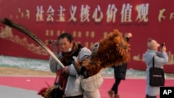 资料照：北京一名街头小贩走过“社会主义核心价值观”的宣传牌。（2024年1月20日）