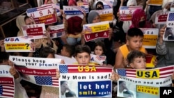 FILE - Afghan refugees hold placards in Islamabad, Pakistan, July 21, 2023. Thousands of Afghans are still waiting to be relocated to the United States.
