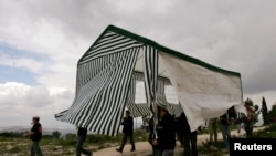 FILE - Jewish settlers carry a tent in the abandoned Jewish settlement of Homesh, in the northern West Bank.