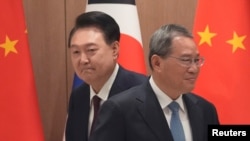 South Korean President Yoon Suk Yeol and Chinese Premier Li Qiang move their positions during a meeting at the Presidential Office in Seoul, South Korea, May 26, 2024.