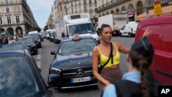 A woman speaks to a police officer at the security perimeter set up for the Olympic Games in Paris, July 18, 2024.