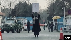 FILE - A young woman protests against a Taliban ban on women's higher education, outside Kabul University, as Taliban guards stand by, in Kabul, Afghanistan, Dec. 25, 2022. Only male students will be allowed to attend state-run universities when they re-open March 6, 2023.