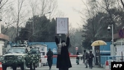 Seorang perempuan muda melakukan aksi protes seorang diri terhadap larangan bagi perempuan untuk menempuh bangku pendidikan tinggi yang diterapkan oleh Taliban, di luar Universitas Kabul di Afghanistan, pada 25 Desember 2022. (Foto: AFP)