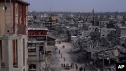 FILE - Palestinians walk through the destruction in the wake of an Israeli air and ground offensive in Khan Younis, southern Gaza Strip, April 8, 2024. 