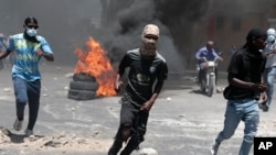 FILE — Protesters run for cover from tear gas fired by police during a protest against insecurity in Port-au-Prince, Haiti, Aug. 7, 2023. 