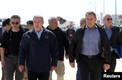 FILE - Turkish Defense Minister Hulusi Akar and Greek Defense Minister Nikos Panagiotopoulos walk as they visit earthquake stricken areas in Turkey, April 4, 2023. (Defense Ministry/Handout via Reuters)