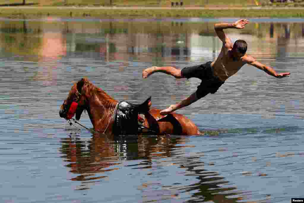 A man jumps from a horse into the Iber River to cool off from hot weather in Mitrovica, Kosovo, June 18, 2024. 