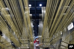 Seorang pekerja mengatur filamen mentah di basis produksi Zhongfu Shenying Carbon Fiber Co., Ltd. di Xining, Provinsi Qinghai, China barat laut pada 22 Februari 2023. (Wu Gang/Xinhua via AP)